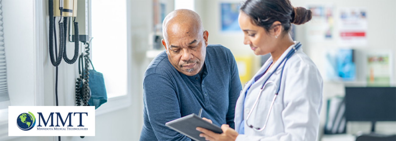 Older man looking at tablet with healthcare professional in exam room