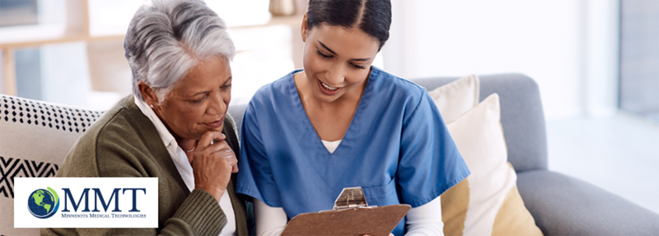 Elderly woman sitting on couch and reviewing information on clipboard with a female healthcare professional