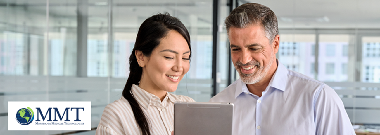 Male and female healthcare professional looking at tablet together and smiling