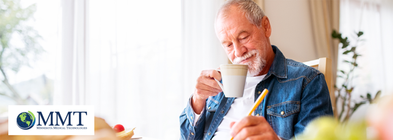 Man drinking coffee in his chair at home while writing