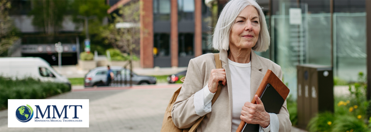 Image shows older woman carrying books and shoulder bag in urban setting