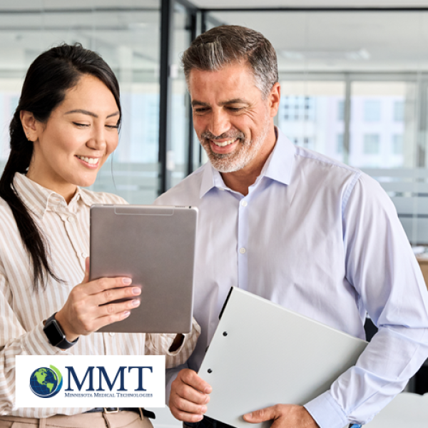 Male and female healthcare professional looking at tablet together and smiling