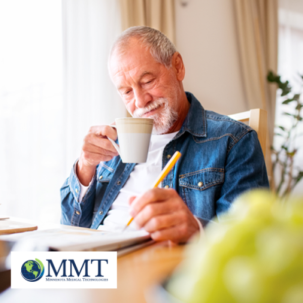 Man drinking coffee in his chair at home while writing