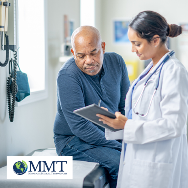 Older man looking at tablet with healthcare professional in exam room