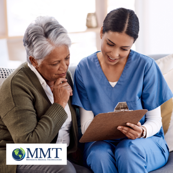 Elderly woman sitting on couch and reviewing information on clipboard with a female healthcare professional