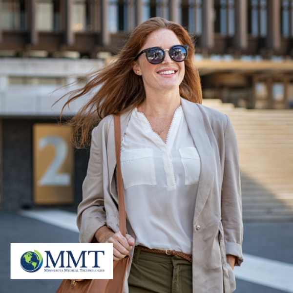 Happy confident woman walking outdoors with sunglasses on