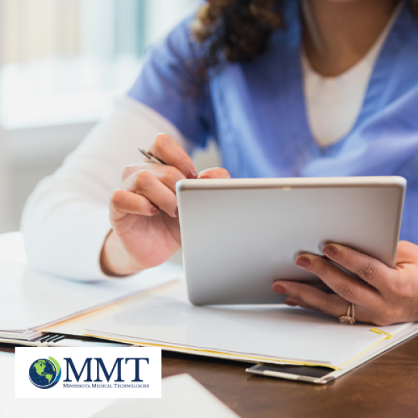Image shows clinician using tablet at a table with other documents